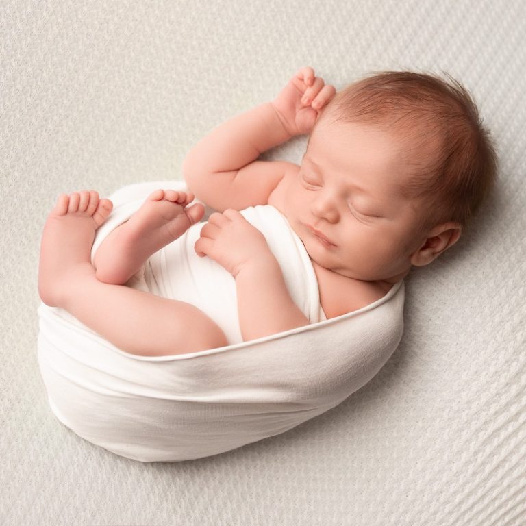 Newborn baby in white wrap in Buckinghamshire studio